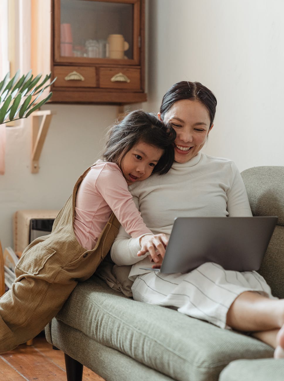 happy mother using laptop with daughter at home