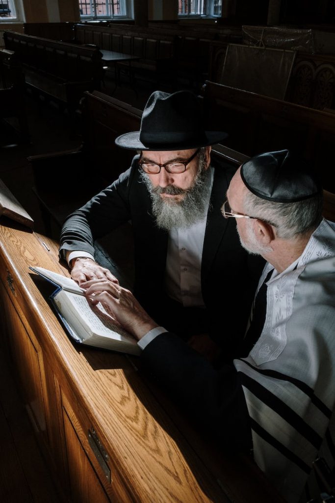 two elderly men sitting on wooden pew