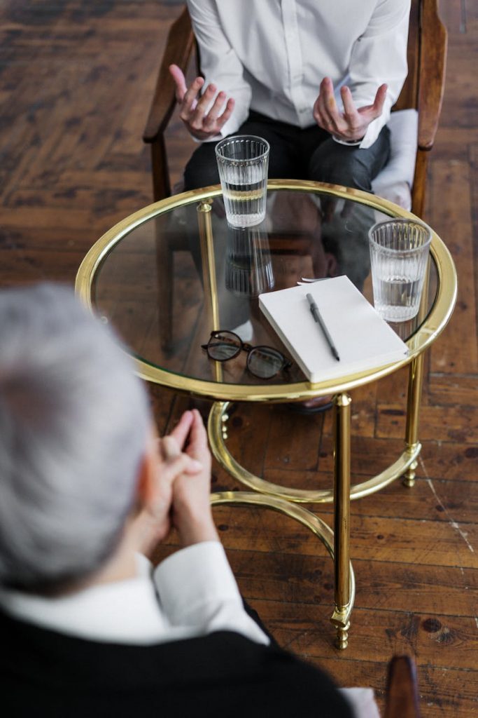 woman in black long sleeve shirt sitting on brown wooden chair - the trouble with psychiatry