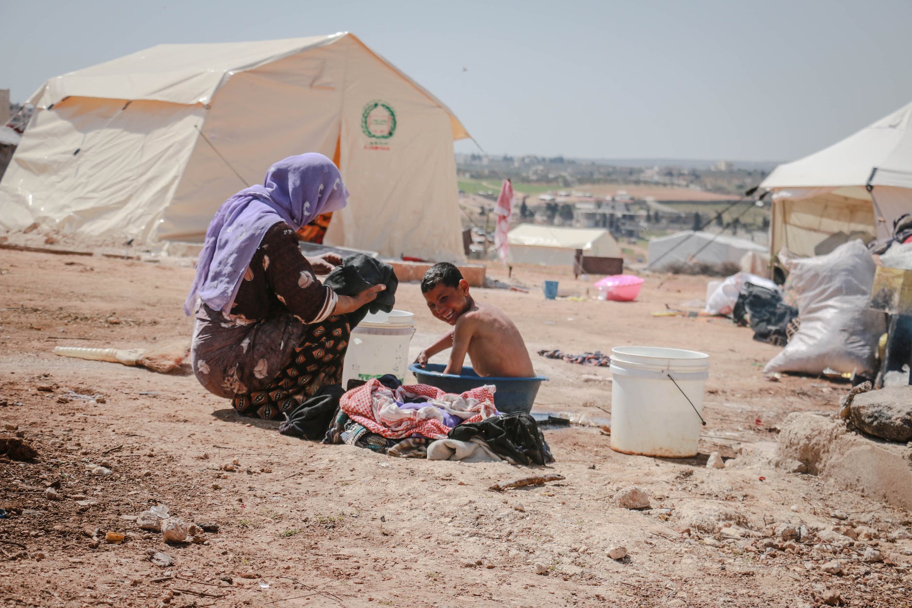 a mother washing a child in a plastic tub