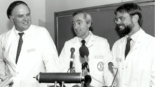 three smiling men wearing robes standing in front of microphones